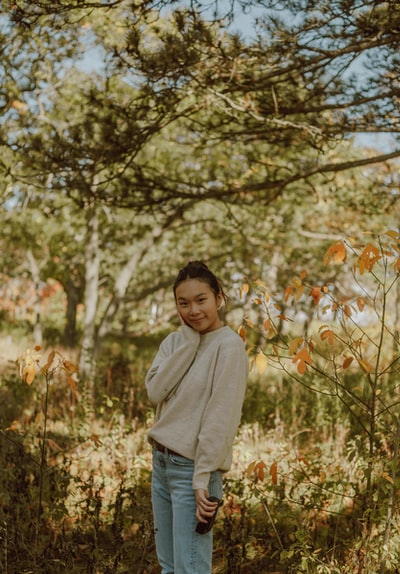 During the day, the boy in a gray hoodie stood in brown grass
